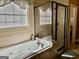 Bathroom featuring a large bathtub with jets, tile floors, and a glass shower at 108 Caraway Rd, Locust Grove, GA 30248