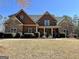 Beautiful home with stone accents, a covered porch, green shutters, and manicured landscaping at 108 Caraway Rd, Locust Grove, GA 30248