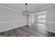 Elegant dining room featuring modern chandelier, large window, and stylish gray wood flooring at 253 Summit View Dr, Mcdonough, GA 30253