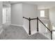 Upstairs hallway with a wooden railing, gray carpet, and natural light, offering a bright and welcoming transition between rooms at 253 Summit View Dr, Mcdonough, GA 30253