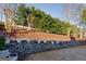 Backyard view showcasing a stone retaining wall, neatly arranged potted plants, white bench, and mature trees at 4030 Cresent Walk Ne Ln, Suwanee, GA 30024