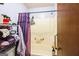 Bathroom with standard shower/tub combo with purple shower curtain and towels within shelving unit at 9100 Settlers Grove Ne Rd, Covington, GA 30014