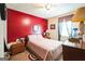 Bedroom with red accent wall, light pink comforter, small windows with curtains, carpet, and dresser at 9100 Settlers Grove Ne Rd, Covington, GA 30014