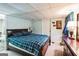 Bedroom with blue plaid comforter, light blue walls, and small window with dark wood dresser at 9100 Settlers Grove Ne Rd, Covington, GA 30014