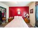 Bedroom with red accent wall, light pink comforter, carpet, curtains, dresser and clothing rack at 9100 Settlers Grove Ne Rd, Covington, GA 30014