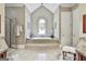 Luxurious bathroom featuring a tiled platform tub, arched window, and granite countertops at 310 Westbourne Dr, Tyrone, GA 30290