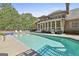 Enjoy a large, modern pool with a built-in spa and covered patio in this well-designed backyard at 310 Westbourne Dr, Tyrone, GA 30290