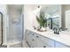 Bright bathroom featuring double vanity, sleek black fixtures, large mirror, and glass-enclosed shower with marble tiling at 10453 Trellis Lane (Lot 28), Hampton, GA 30228