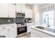 Well-equipped kitchen features white cabinets, stainless appliances, quartz counters and black tiled backsplash at 10453 Trellis Lane (Lot 28), Hampton, GA 30228