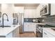 Kitchen features stainless appliances, white cabinets, quartz countertops, and sleek black backsplash at 10453 Trellis Lane (Lot 28), Hampton, GA 30228