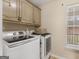 Bright laundry room with modern appliances, built-in cabinets, and a window at 180 Collins Way, Locust Grove, GA 30248