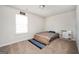 Neutral colored bedroom with carpet, large window letting in natural light and sign reading, 