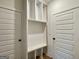 Bright mudroom features custom shelving, built-in bench, and classic white paneled doors at 6149 Se Pinewood Dr, Covington, GA 30014