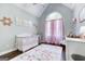 Charming Bedroom with a white crib, floral rug, and arched window with light pink curtains at 3140 Cox Cemetery Rd, Social Circle, GA 30025