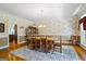 Formal dining room with hardwood floors, decorative wallpaper, and a rustic wooden dining table at 122 Lawn Market, Sharpsburg, GA 30277