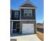 Two-story townhome featuring dark siding, brick base, and a one-car garage in a community setting at 223 Ivey Ter # 34, Temple, GA 30179