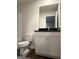 Bathroom with a white vanity, dark countertop, toilet, and large mirror at 231 Ivey Ter # 38, Temple, GA 30179