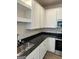 Kitchen featuring a stainless steel sink, black countertops, and white cabinetry at 231 Ivey Ter # 38, Temple, GA 30179