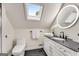 This bathroom features a vanity with dark countertops, a round mirror, and a skylight at 1471 Hardin Ave, College Park, GA 30337