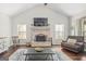 Cozy living room with a brick fireplace, vaulted ceilings, and natural light from large windows at 624 Bexley Rd, Moreland, GA 30259
