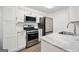 Well-lit kitchen showcases stainless steel appliances, white cabinets, granite countertops, and luxury vinyl plank flooring at 1379 Keys Lake Ne Dr, Brookhaven, GA 30319