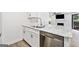 Close-up of kitchen with granite countertops, stainless steel dishwasher and sink, and white cabinets with black hardware at 1379 Keys Lake Ne Dr, Brookhaven, GA 30319