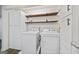 Well-lit laundry room boasts side-by-side washer and dryer, floating shelves, white cabinets, and vinyl plank flooring at 1379 Keys Lake Ne Dr, Brookhaven, GA 30319
