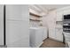 Clean laundry room featuring a side-by-side washer and dryer, sleek floating shelves, and additional storage cabinetry at 1379 Keys Lake Ne Dr, Brookhaven, GA 30319