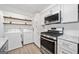 Laundry area with stainless steel gas range, stainless steel microwave, and stacked washer and dryer at 1379 Keys Lake Ne Dr, Brookhaven, GA 30319