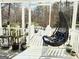 Relaxing porch with a swinging chair, plants, and a view of the wooded backyard at 114 Rolling Grn, Peachtree City, GA 30269