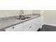 Modern kitchen featuring granite countertops, stainless steel sink, and white cabinets, complemented by stylish black tile flooring at 2589B Se Fieldstone View Ln, Conyers, GA 30013