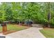 View of a gray home with a concrete driveway, surrounded by mature trees and lush landscaping at 125 Marilyn Ct, Fayetteville, GA 30214
