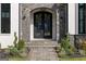 Ornate black metal front door with stone archway and walkway, enhanced by manicured landscaping at 4100 Oak Hill Rd, Douglasville, GA 30135