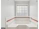 Close up of a white bathtub with window and red accent tile at 848 Gateshead Ct, Lawrenceville, GA 30043
