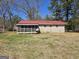 View of the back of the brick house, with a screened-in porch and a red metal roof at 216 E Richardson St, Oxford, GA 30054