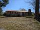 Charming single-story brick home with a red metal roof, a chimney, and a spacious front yard at 216 E Richardson St, Oxford, GA 30054