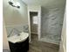 Bathroom featuring a vanity and a walk-in shower with marble-style tile at 9184 Thrash Sw St, Covington, GA 30014
