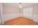 Classic dining room with wainscoting, hardwood floors, a modern chandelier, and bright window at 5120 Redcoat Ln, Mcdonough, GA 30252