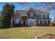 Charming two-story brick home with a well-manicured lawn and mature trees on a sunny day at 5120 Redcoat Ln, Mcdonough, GA 30252