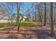 View of a large wooded backyard with a multi-car garage home in the distance at 707 Orleans Trce, Peachtree City, GA 30269