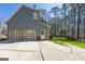 View of a three car garage home with an entrance door and landscaped greenery at 707 Orleans Trce, Peachtree City, GA 30269