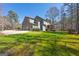 View of the rear of a home with a three car garage, screened in porch, and a large yard at 707 Orleans Trce, Peachtree City, GA 30269