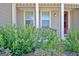 Inviting front porch featuring a red door, white columns, a bench, and lush landscaping at 135 Red Maple Dr, Peachtree City, GA 30269