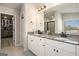 Well-lit bathroom with double sinks, gray countertops, white cabinets, and access to the walk-in closet at 157 Donovan Ave, Locust Grove, GA 30248