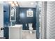 A traditional bathroom featuring navy walls, a white vanity, and a tile shower with a shower curtain at 157 Donovan Ave, Locust Grove, GA 30248