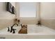 Soaking tub featuring a light tile surround, a window with blinds, and dark faucet fixtures at 157 Donovan Ave, Locust Grove, GA 30248