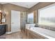 Bright bathroom featuring a soaking tub with tile surround, walk-in shower, and a window at 1283 Heritage Dr, Villa Rica, GA 30180