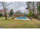 Wide shot of backyard, featuring a pool, brick home, and mature trees at 10174 Twin Oaks Sw Dr, Covington, GA 30014