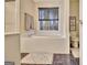 Bathroom featuring a soaking tub, window, and neutral decor, ideal for relaxation at 215 Farr Lake Dr, Tyrone, GA 30290