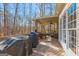 Spacious covered deck featuring outdoor grills, a ceiling fan, and views of the wooded property at 125 Tall Timber Ct, Fayetteville, GA 30215